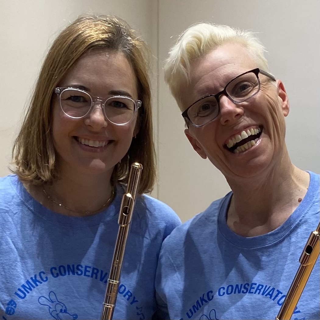 Meret teaching a very young girl to play flute while other students look on